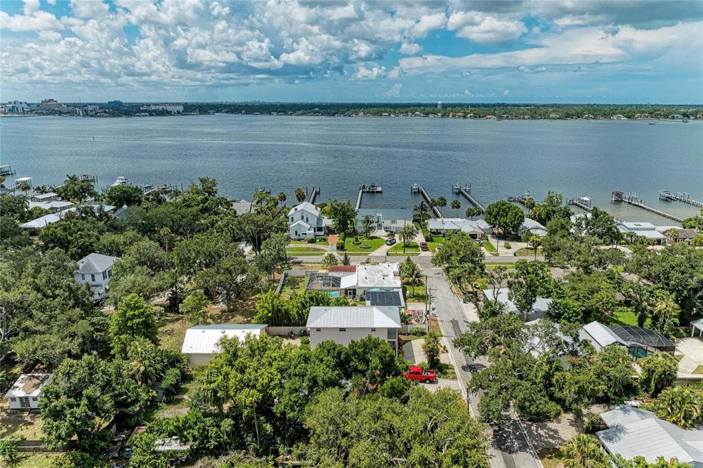 An aerial view shows a coastal neighborhood with houses, lush trees, and private boat docks — 1712 4TH STREET W, PALMETTO, FL