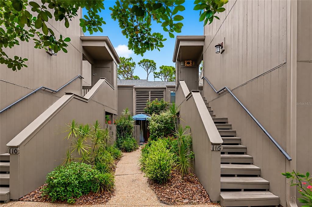 An exterior view shows two staircases leading to upper-level units with a central walkway — 116 WOODLAND PLACE UNIT 116, OSPREY, FL