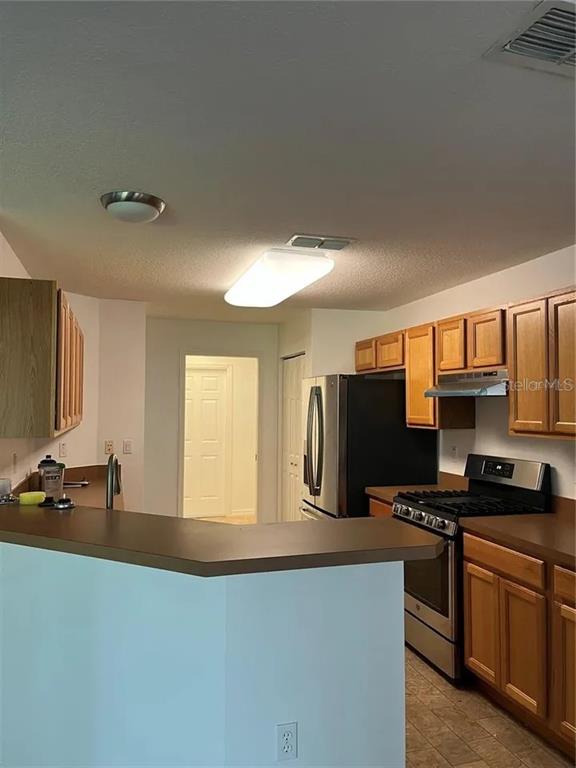 A kitchen features wood cabinets, stainless steel appliances, and a breakfast bar overlooking the room — 8714 SW 83RD LOOP, OCALA, FL