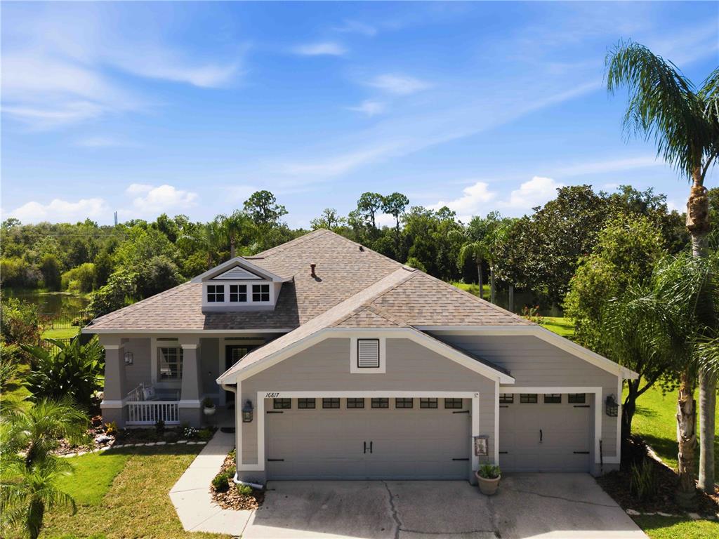 An aerial view of a gray single-story house with a three-car garage and roof dormer — 16817 HARRIERRIDGE PLACE, LITHIA, FL