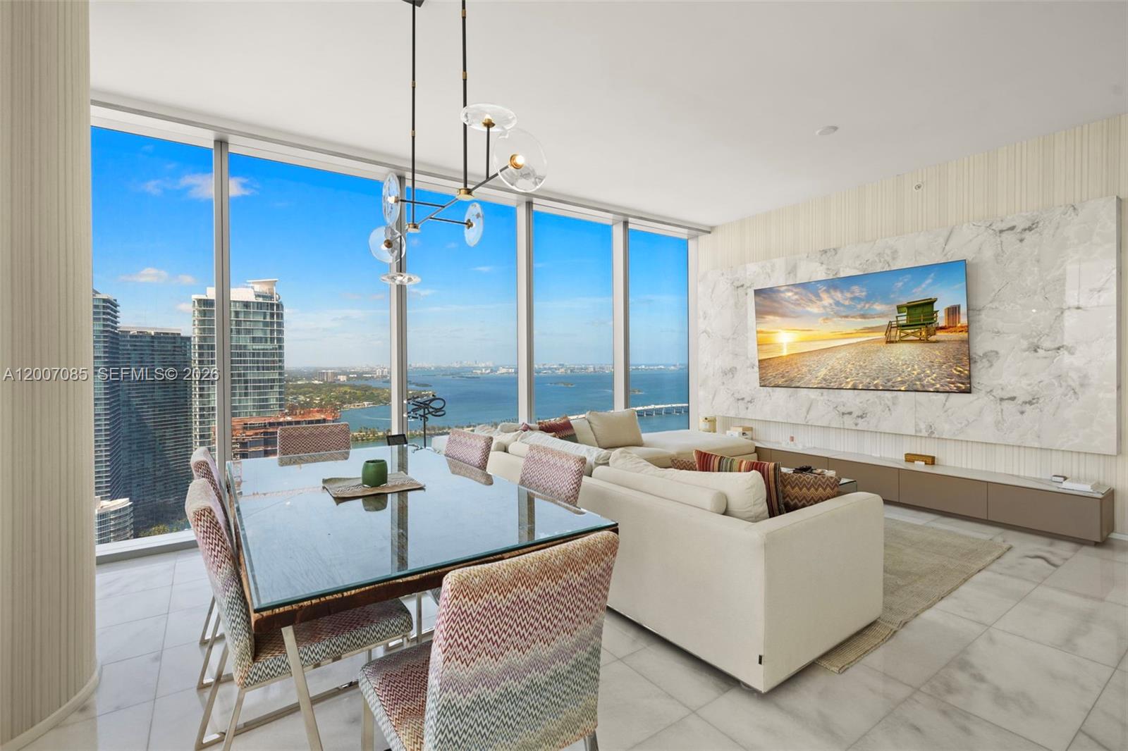 A modern living and dining room features floor-to-ceiling windows, marble flooring, and a television — 700 NE 26th Ter # 4206, Miami FL 33137, MIAMI, FL