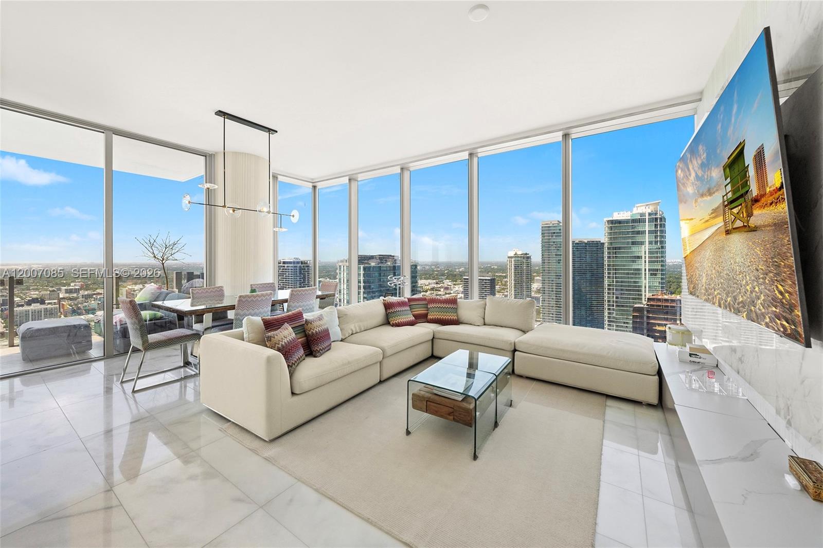 A modern living and dining area features floor-to-ceiling windows with city views and marble flooring — 700 NE 26th Ter # 4206, Miami FL 33137, MIAMI, FL