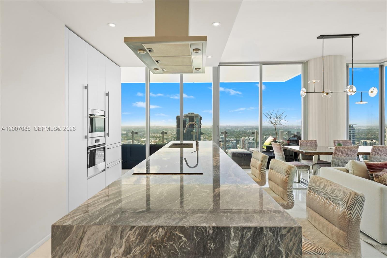 A modern kitchen features a large marble island, white cabinetry, and floor-to-ceiling windows with views — 700 NE 26th Ter # 4206, Miami FL 33137, MIAMI, FL