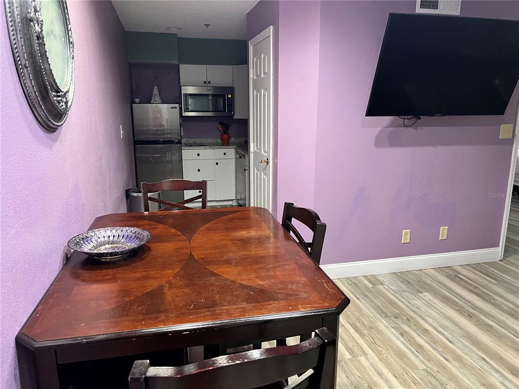 A dining area with a wooden table sits in front of a small kitchen — 3100 PARKWAY BOULEVARD UNIT 521, KISSIMMEE, FL