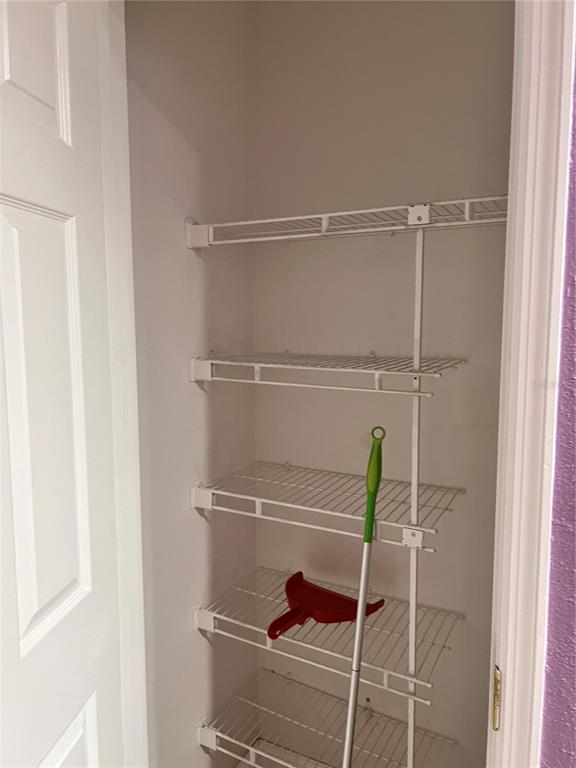 A white wire shelving unit is installed inside a small closet with a broom — 3100 PARKWAY BOULEVARD UNIT 521, KISSIMMEE, FL