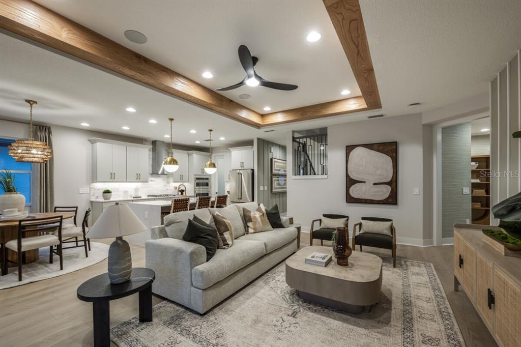An open-concept living room and kitchen feature wood ceiling beams, recessed lighting, and neutral furniture — 13694 LOREDO WAY, PUNTA GORDA, FL