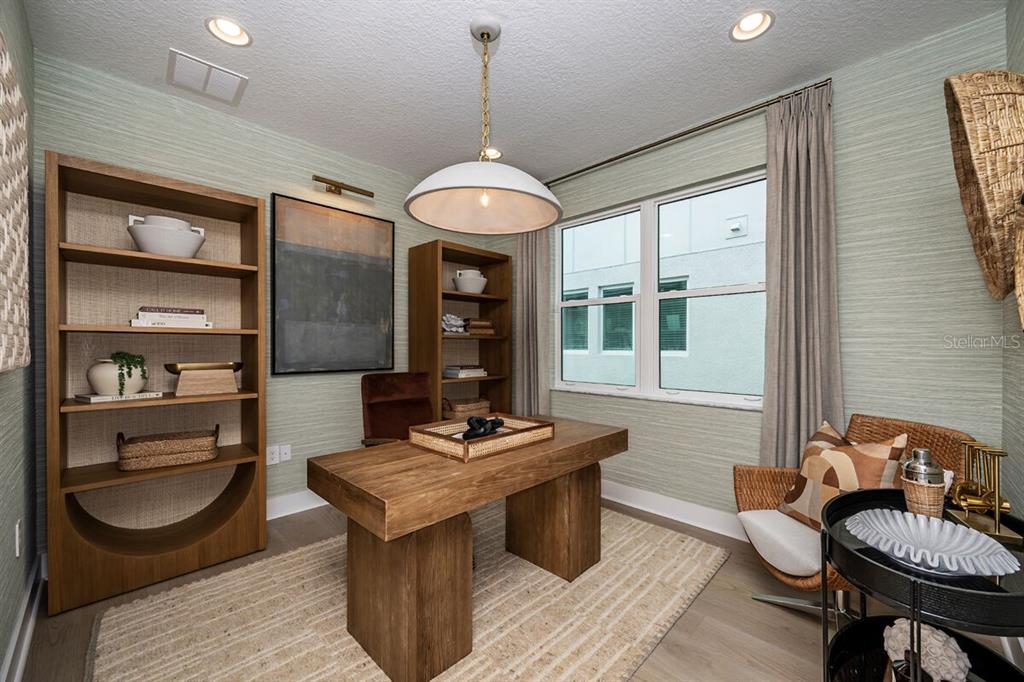 A home office features a wooden desk, two bookshelves, a wicker chair, and green wallpaper — 13694 LOREDO WAY, PUNTA GORDA, FL