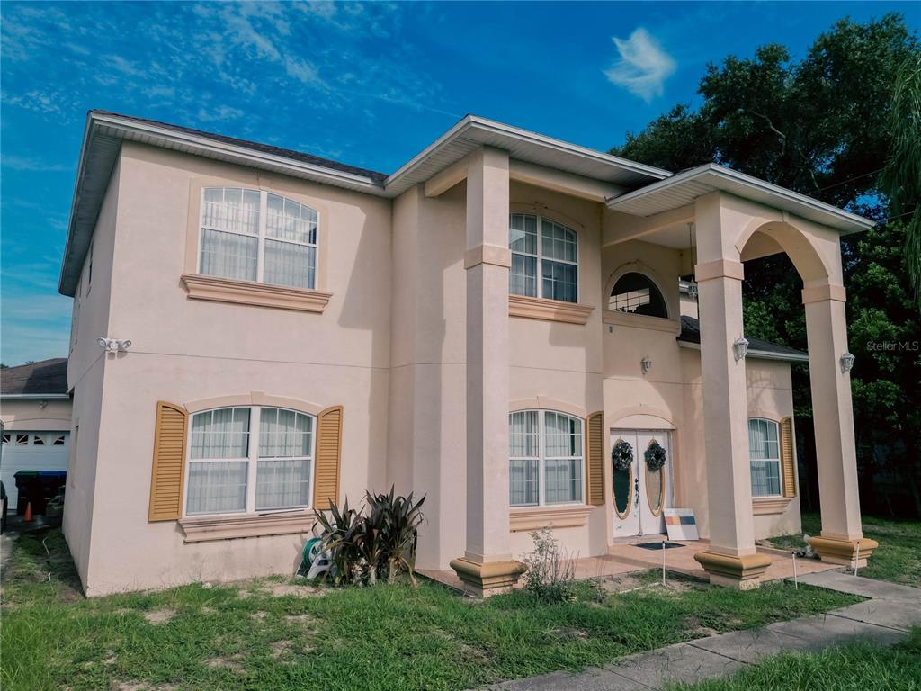 A two-story stucco house features a covered front porch with large columns and arched entryways — 2266 RED GATE ROAD, ORLANDO, FL