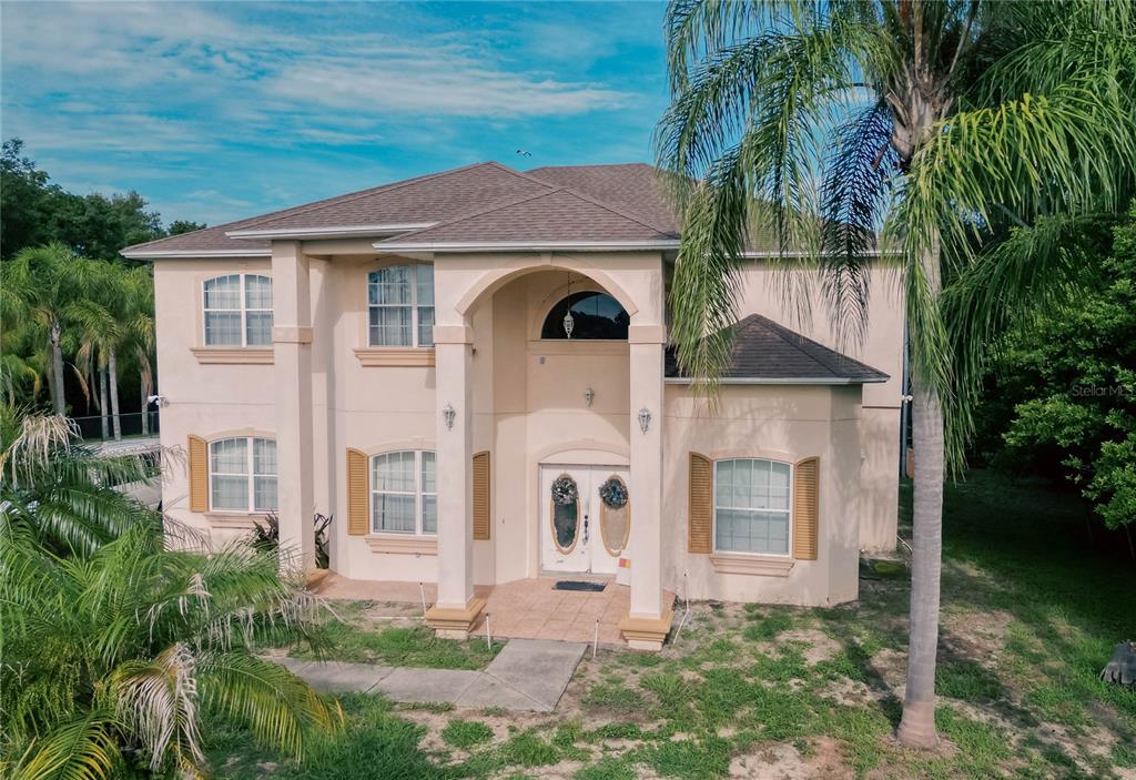 A two-story beige house with a covered entryway and a large palm tree in front — 2266 RED GATE ROAD, ORLANDO, FL