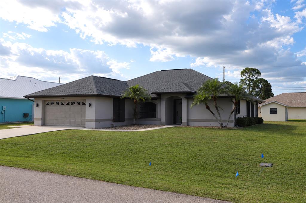 A single-story house with a gray roof, beige stucco exterior, and a two-car garage — 23146 AMBASSADOR AVENUE, PORT CHARLOTTE, FL