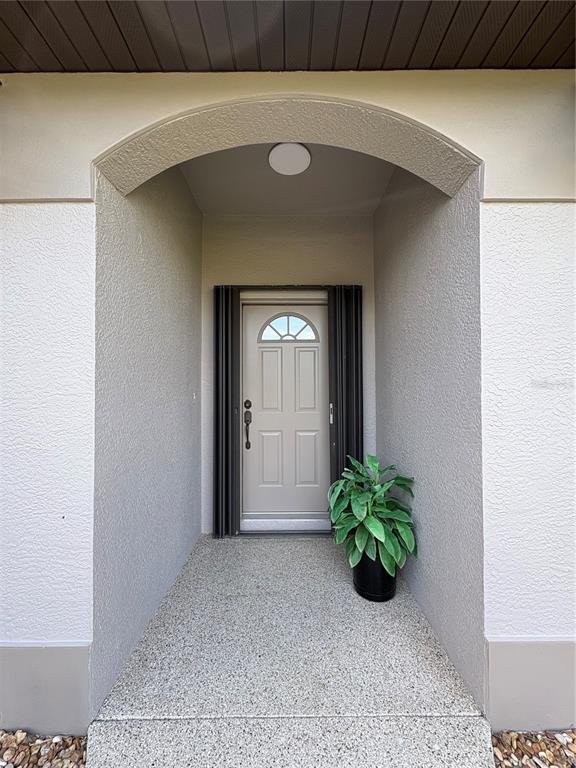 A covered entryway features a light-colored front door with a small arched window — 23146 AMBASSADOR AVENUE, PORT CHARLOTTE, FL