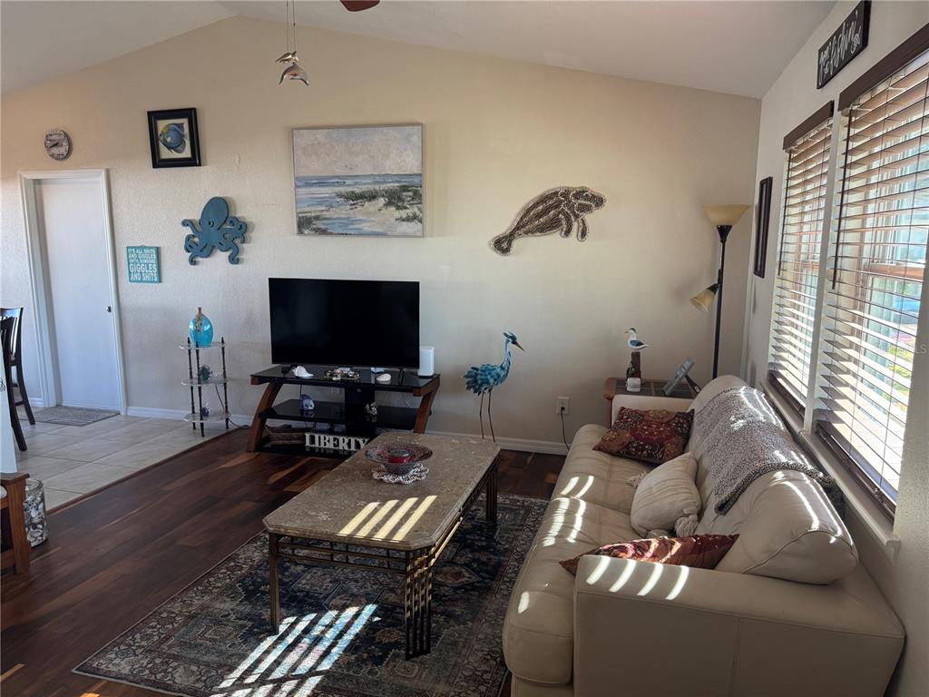 A living room features a television on a stand, a sofa, and coastal-themed wall decor — 4399 MUNDELLA CIRCLE, PORT CHARLOTTE, FL