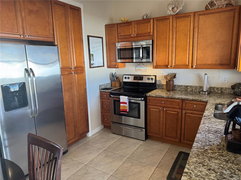 A kitchen features wood cabinets, stainless steel appliances, and granite countertops — 4399 MUNDELLA CIRCLE, PORT CHARLOTTE, FL