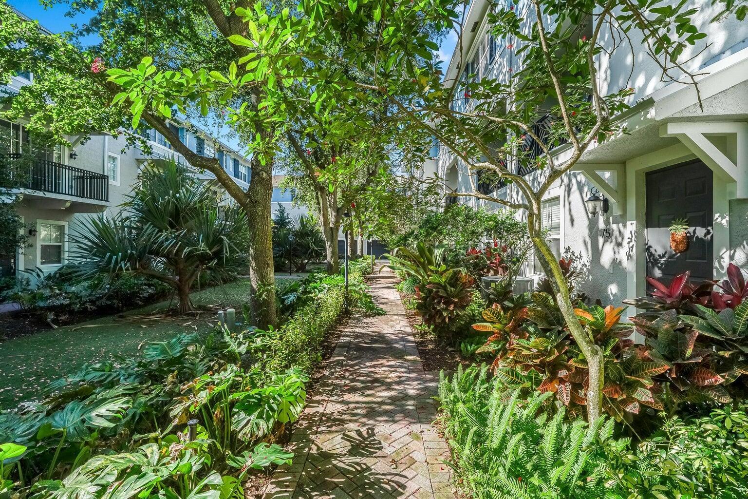 A brick walkway leads between lush tropical landscaping and apartment buildings with balconies — 75 Atlantic Grove Way, Delray Beach FL 33444, DELRAY BEACH, FL