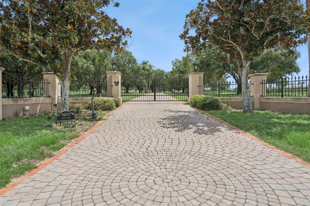 A large tan house with a circular driveway and a covered arched entryway — 9400 LAWS RD, CLERMONT, FL
