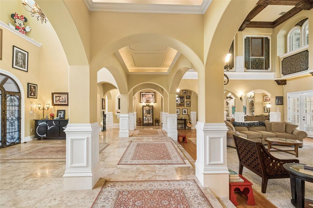 A spacious foyer features arched walkways, stone tile flooring, and multiple area rugs — 9400 LAWS RD, CLERMONT, FL
