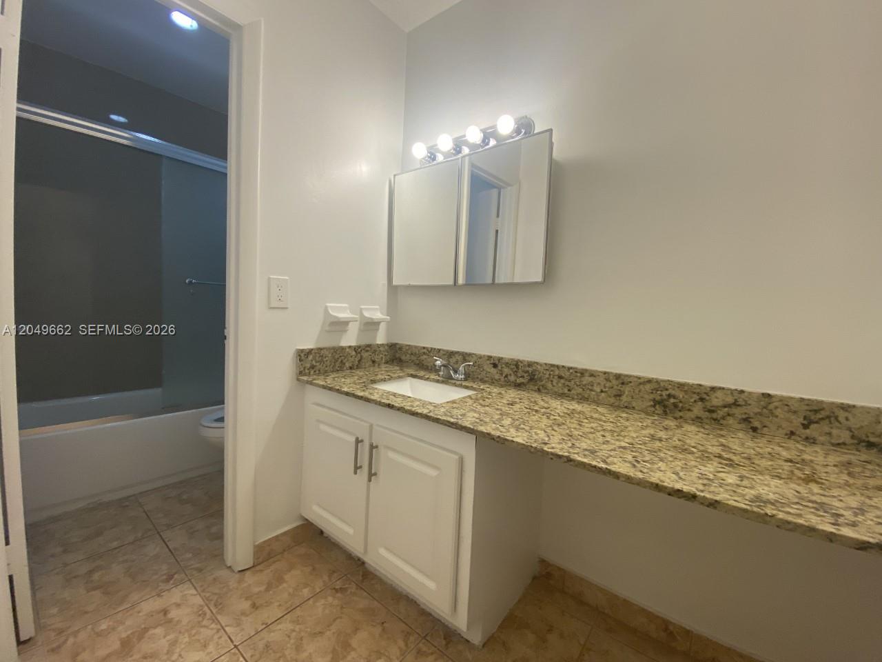 A bathroom features a granite countertop vanity, white cabinets, a medicine cabinet, and tiled flooring — 6501 Winfield Blvd # 53, Margate FL 33063, MARGATE, FL