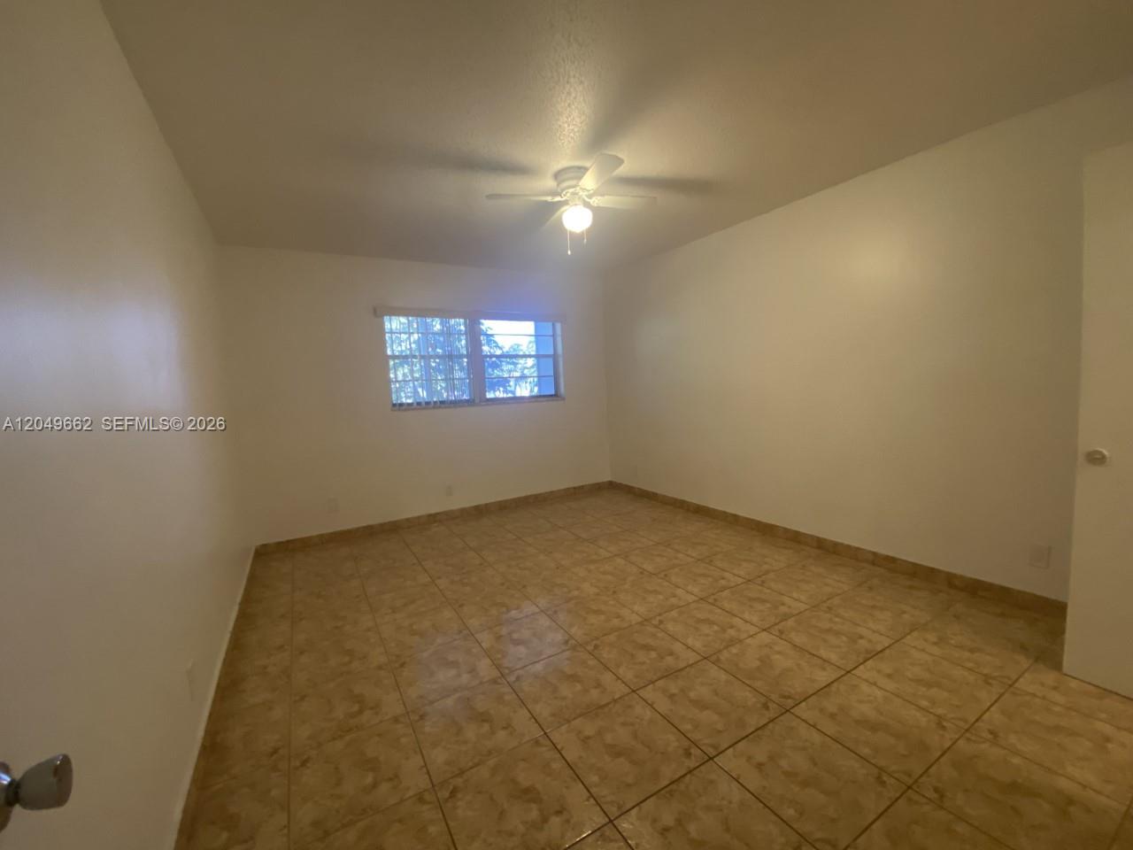 An empty bedroom features beige tile flooring, white walls, and a ceiling fan — 6501 Winfield Blvd # 53, Margate FL 33063, MARGATE, FL