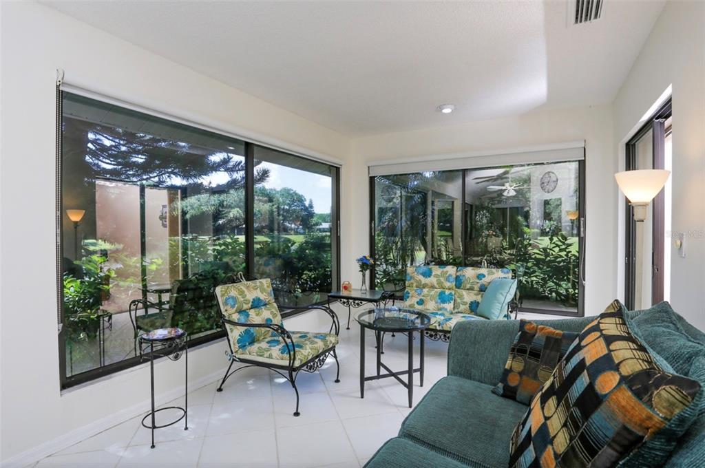 A sunroom with white tile floors, large glass sliding doors, and casual patio-style furniture — 226 SOUTHAMPTON LANE UNIT 257, VENICE, FL