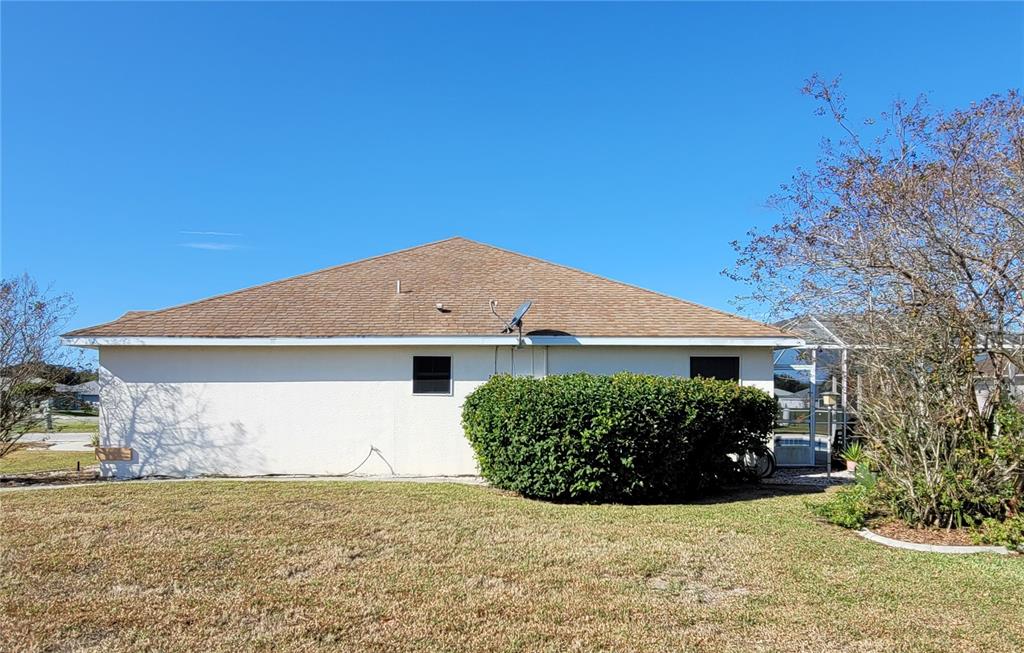 The exterior of a house features a tan shingled roof, white stucco walls, and landscaping — 4773 NW 32ND STREET, OCALA, FL
