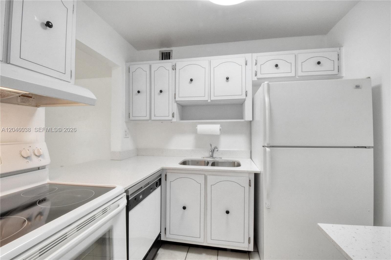 A white kitchen features a stove, dishwasher, sink, refrigerator, and upper and lower cabinets — 10387 N Kendall Dr # R2, Miami FL 33176, MIAMI, FL