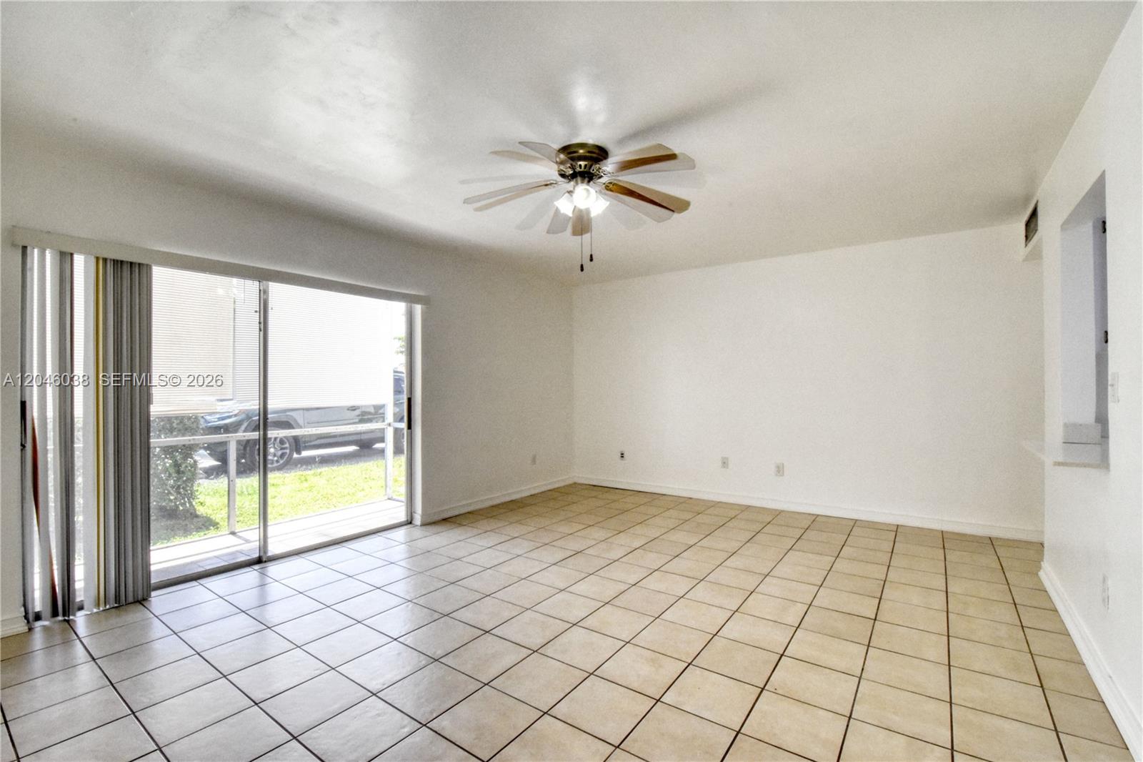 An empty room features beige tile flooring, white walls, a ceiling fan, and sliding glass doors — 10387 N Kendall Dr # R2, Miami FL 33176, MIAMI, FL