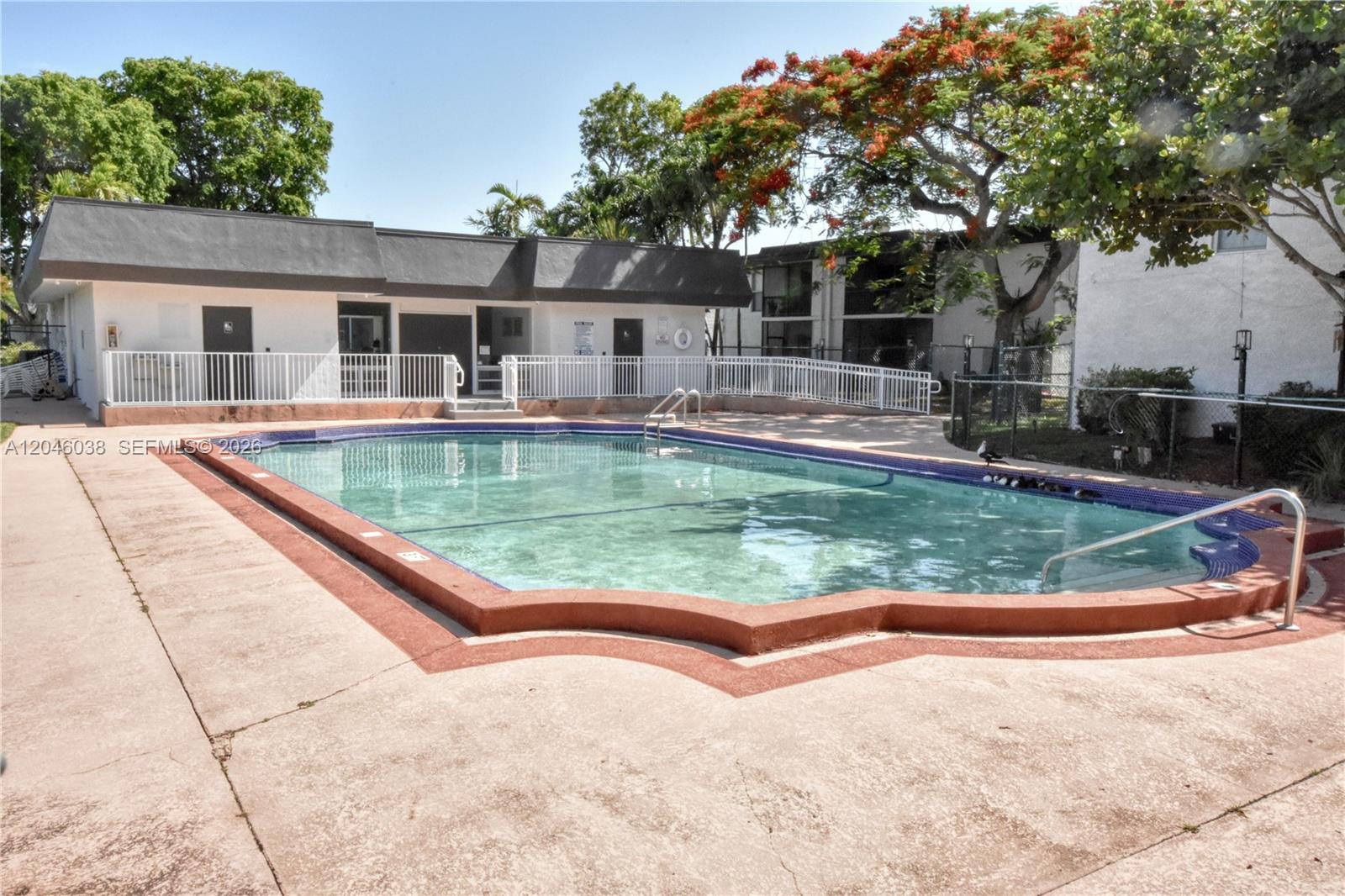 An outdoor swimming pool with a red border sits in front of a white building — 10387 N Kendall Dr # R2, Miami FL 33176, MIAMI, FL