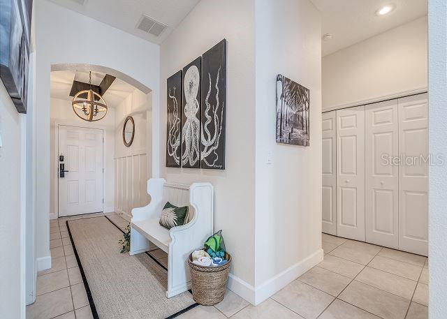 A foyer features a white bench, an octopus triptych, and a light fixture near a door — 1200 CINNAMON BEACH WAY UNIT 1124, PALM COAST, FL