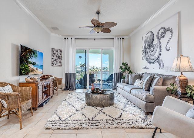 A living room features a gray sofa, a wicker chair, and a large octopus wall art — 1200 CINNAMON BEACH WAY UNIT 1124, PALM COAST, FL
