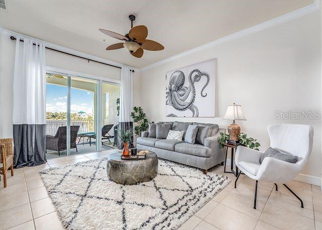 A living room features a gray sofa, white accent chair, octopus wall art, and balcony access — 1200 CINNAMON BEACH WAY UNIT 1124, PALM COAST, FL