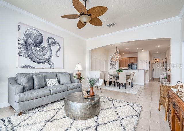 A living room features a gray sofa, a round metal coffee table, and an octopus painting — 1200 CINNAMON BEACH WAY UNIT 1124, PALM COAST, FL