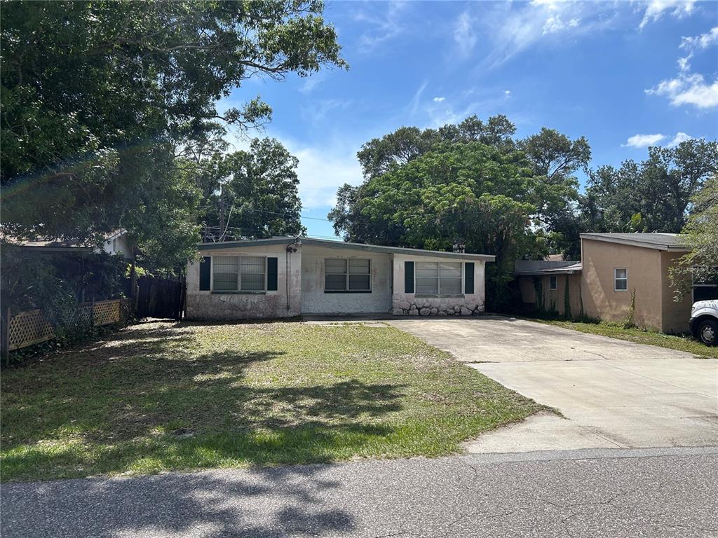 A single-story house with a concrete driveway and a front lawn under mature trees — 6328 30TH WAY N, ST PETERSBURG, FL