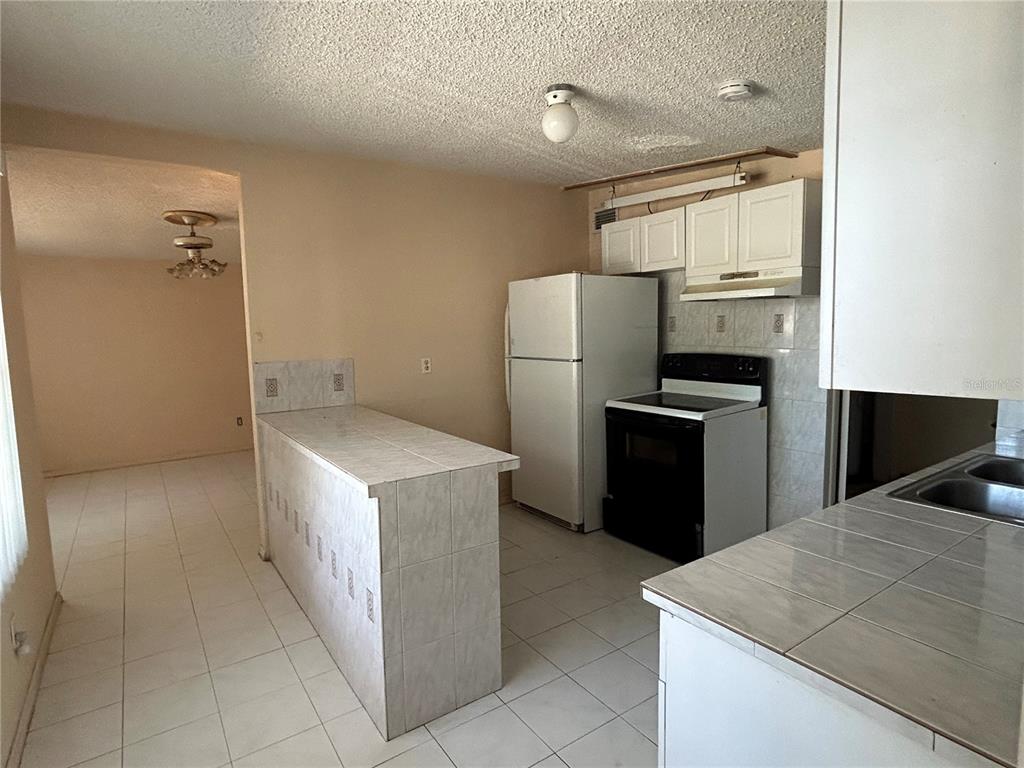A kitchen features white tiled countertops, a white refrigerator, a black stove, and tiled floors — 6328 30TH WAY N, ST PETERSBURG, FL