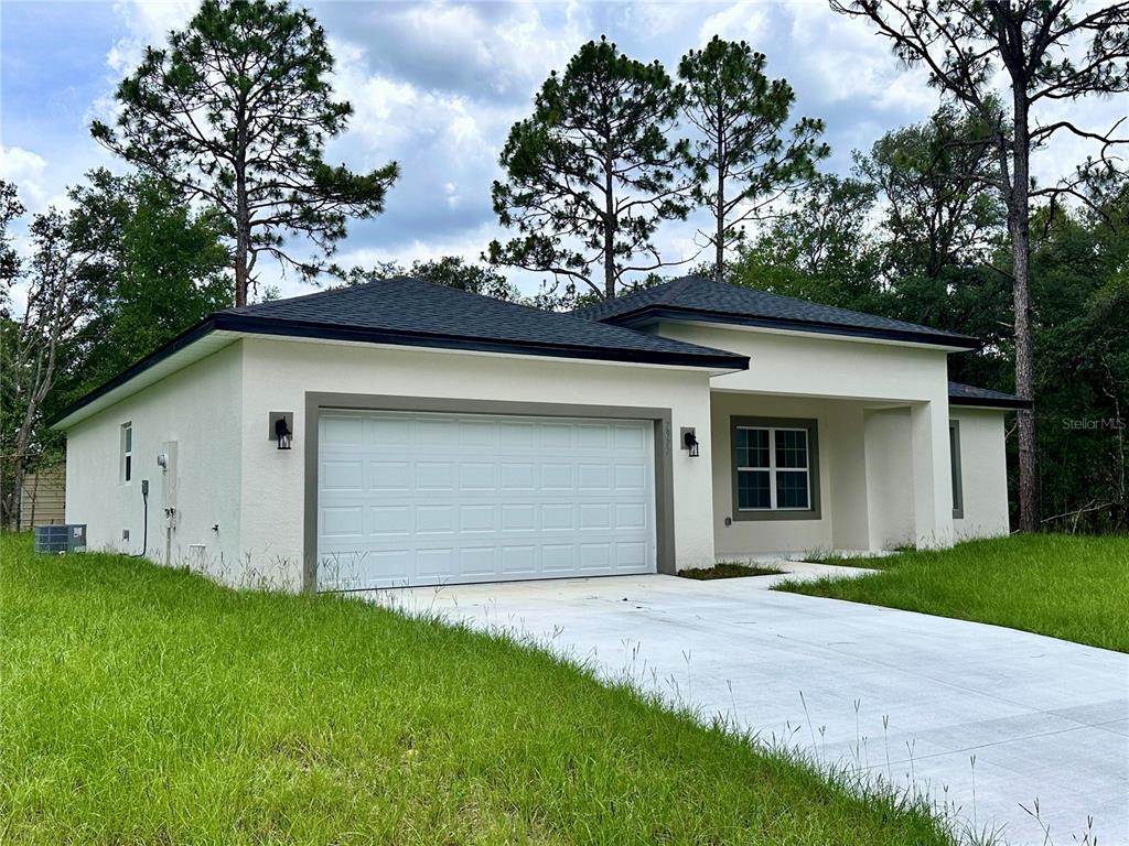 A single-story house with a white stucco exterior, a two-car garage, and a concrete driveway — 7977 N POCONO DRIVE, CITRUS SPRINGS, FL