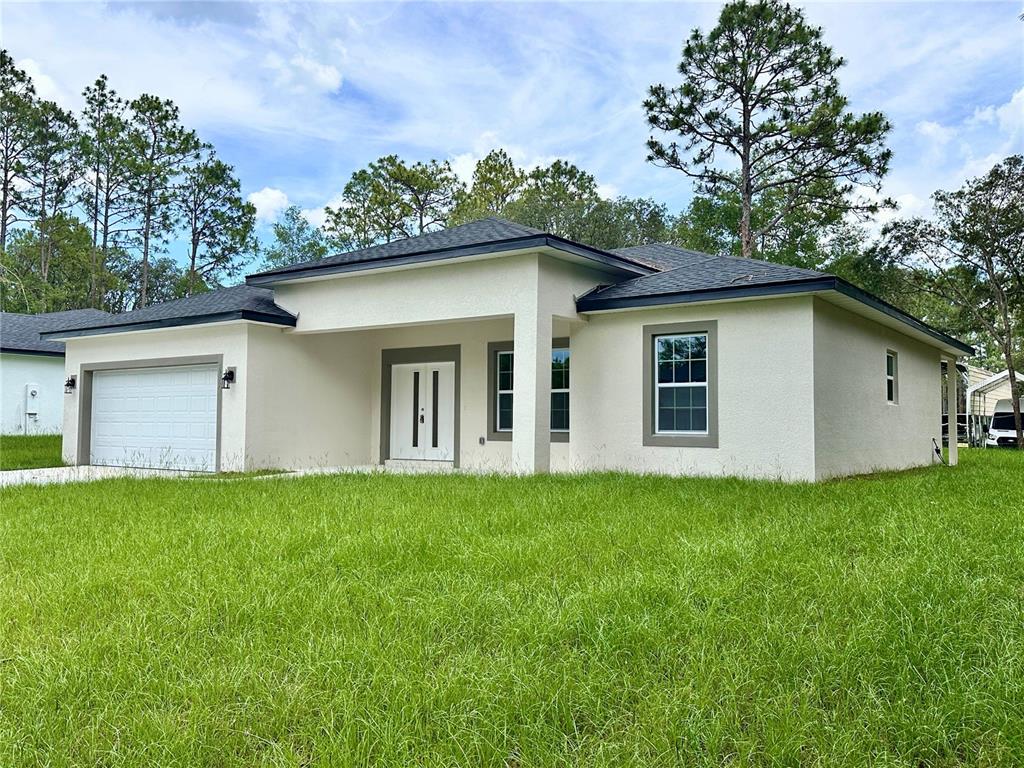 A single-story house with a white stucco exterior, gray trim, and a two-car garage — 7977 N POCONO DRIVE, CITRUS SPRINGS, FL