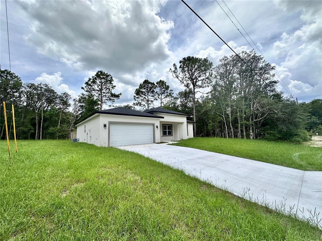 A white, single-story house with a two-car garage sits on a grassy lot — 7977 N POCONO DRIVE, CITRUS SPRINGS, FL