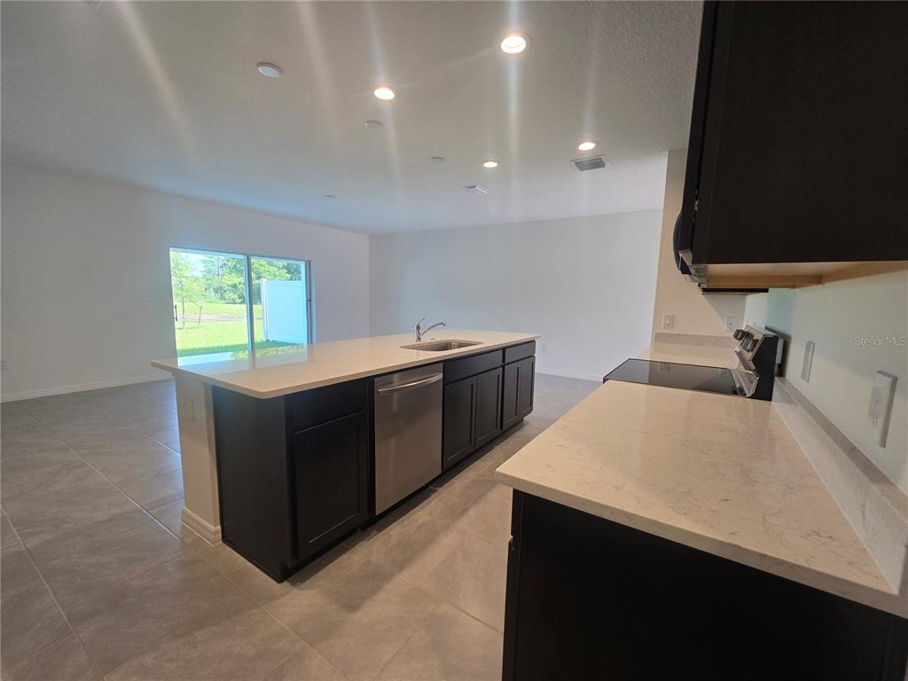 A modern kitchen features dark cabinets, white countertops, stainless steel appliances, and tile flooring — 2552 STARRY POINT, ST CLOUD, FL
