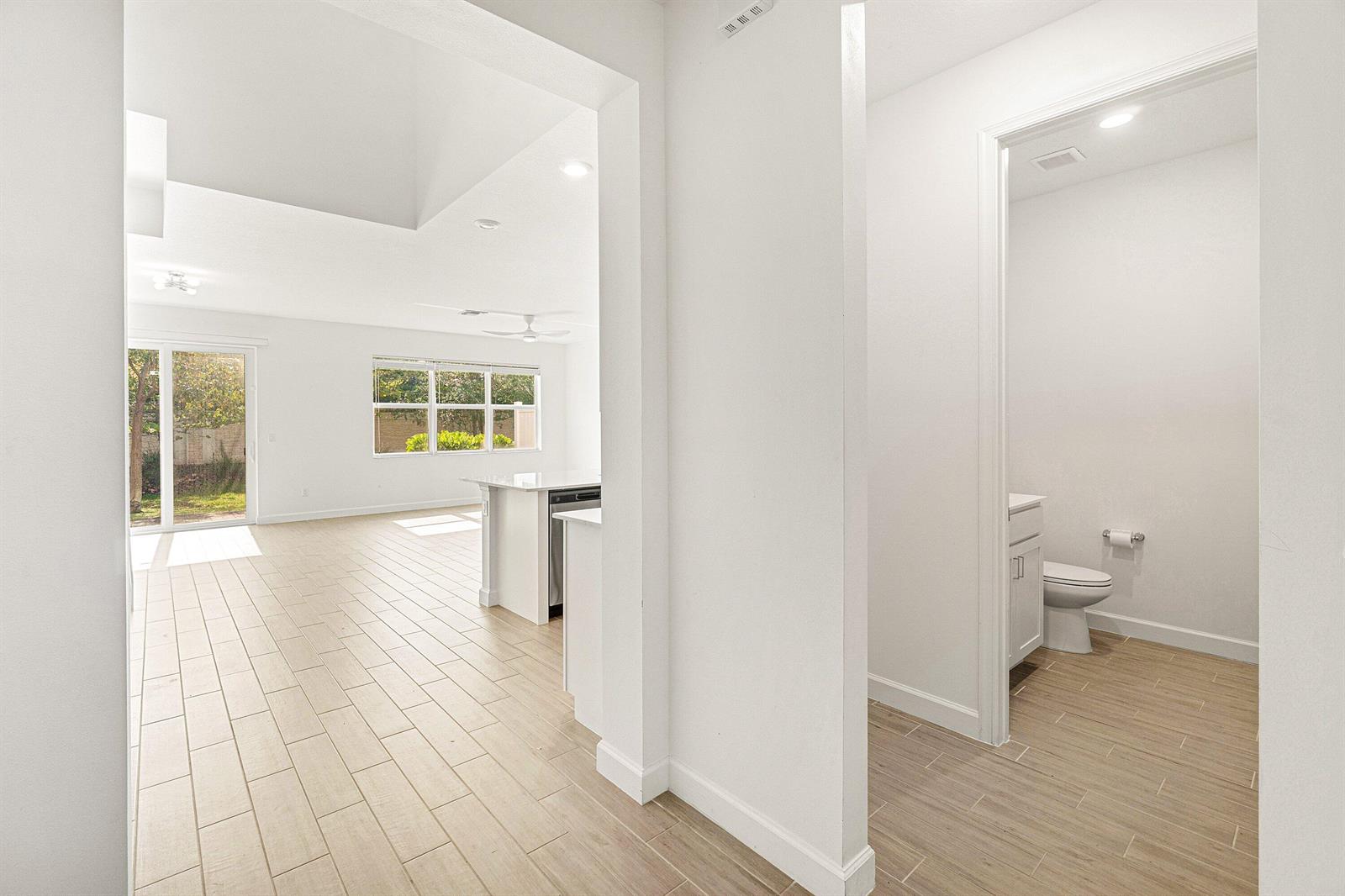 A view from a hallway looking into a bright living area and a small bathroom — 4969 Navali Drive, Lake Worth FL 33467, LAKE WORTH, FL