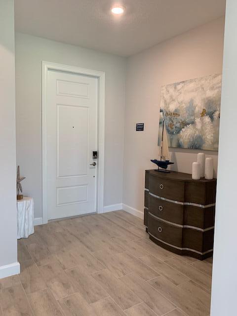 An entryway features light wood-look tile flooring, a white front door, and a wooden chest — 4969 Navali Drive, Lake Worth FL 33467, LAKE WORTH, FL