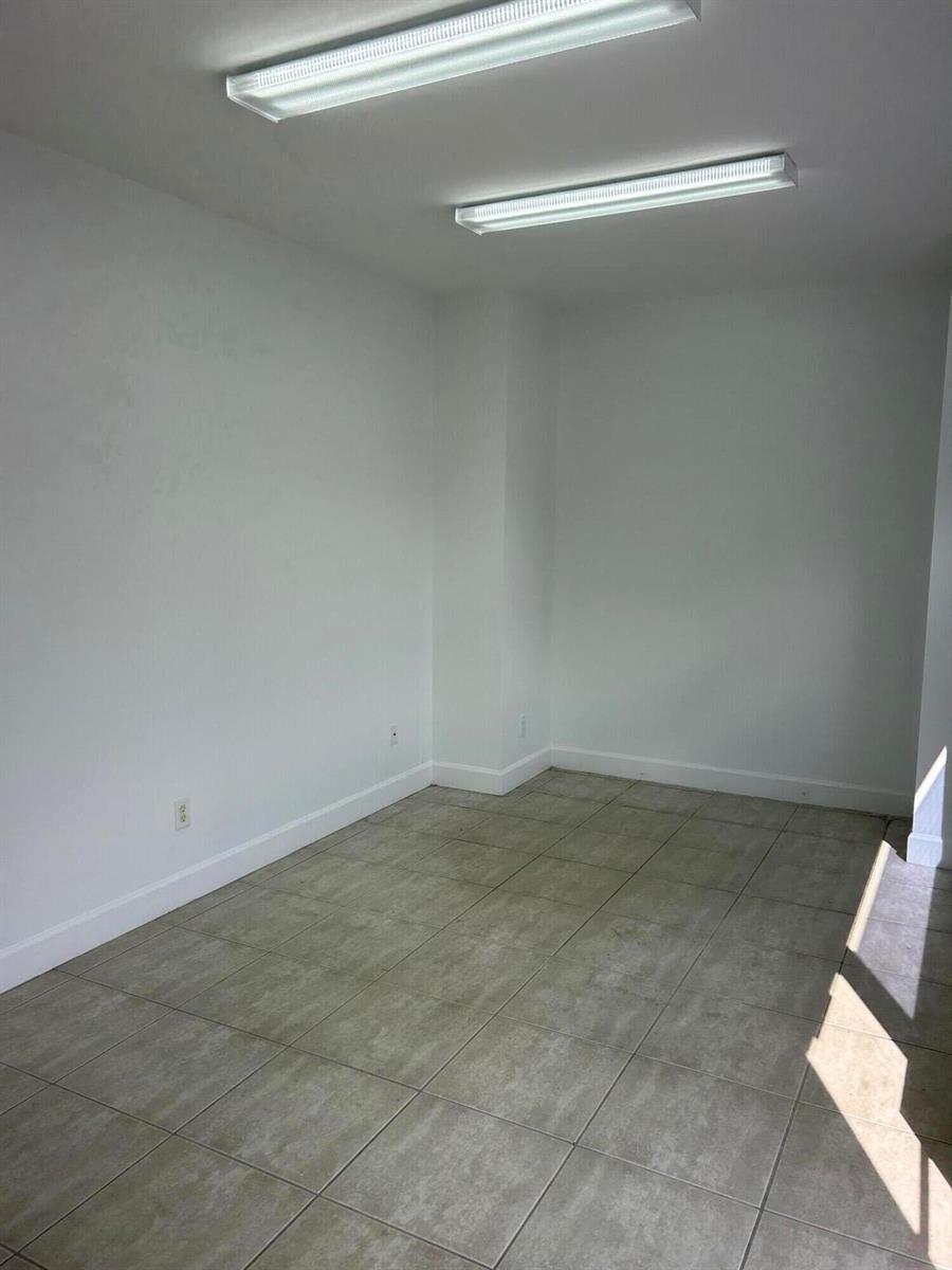 An empty room with white walls, tile flooring, and two rectangular ceiling light fixtures — 1746 SW Biltmore Street # 1746, FL 34984, FL