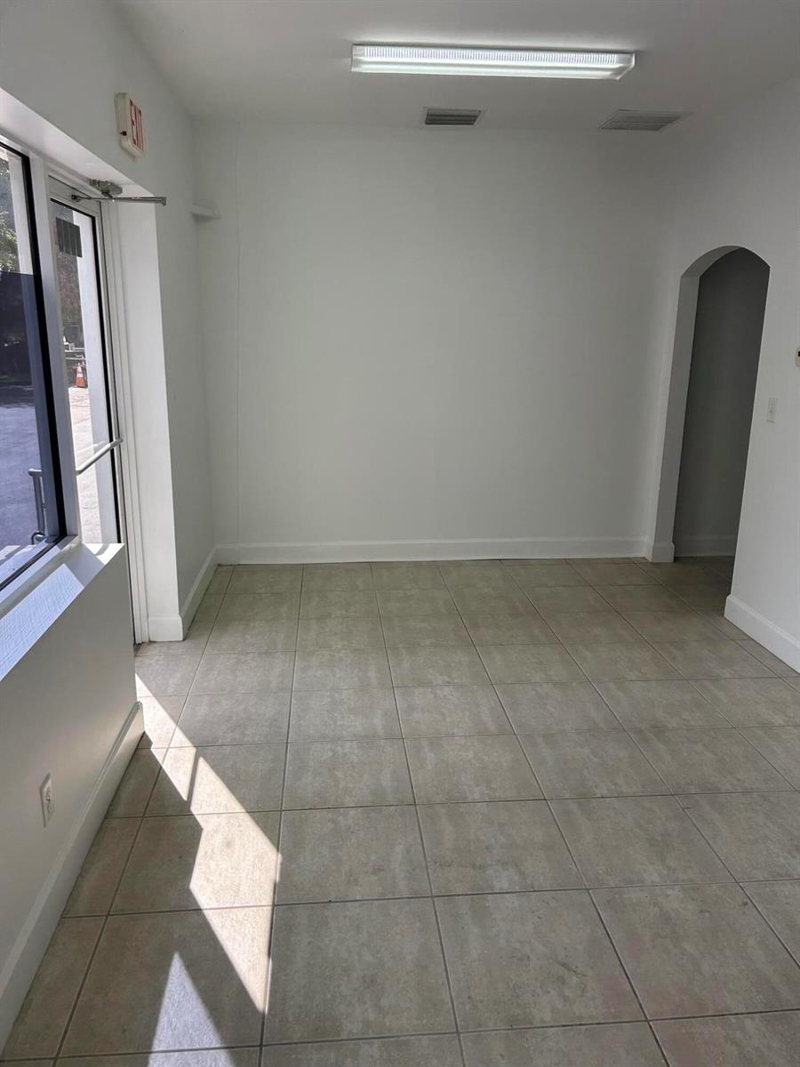 An empty room with beige tile flooring, white walls, and an arched doorway — 1746 SW Biltmore Street # 1746, FL 34984, FL