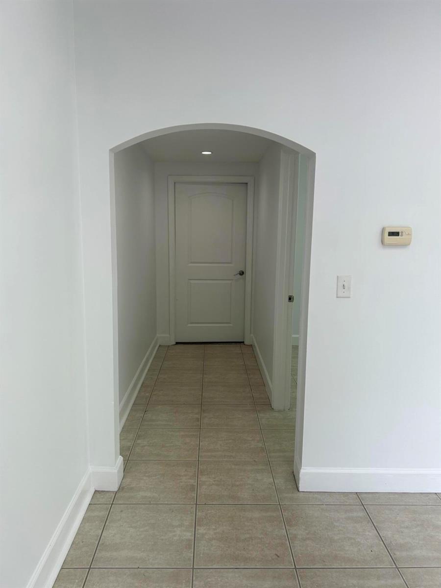 A tiled hallway leads to a closed white door through an arched entryway — 1746 SW Biltmore Street # 1746, FL 34984, FL