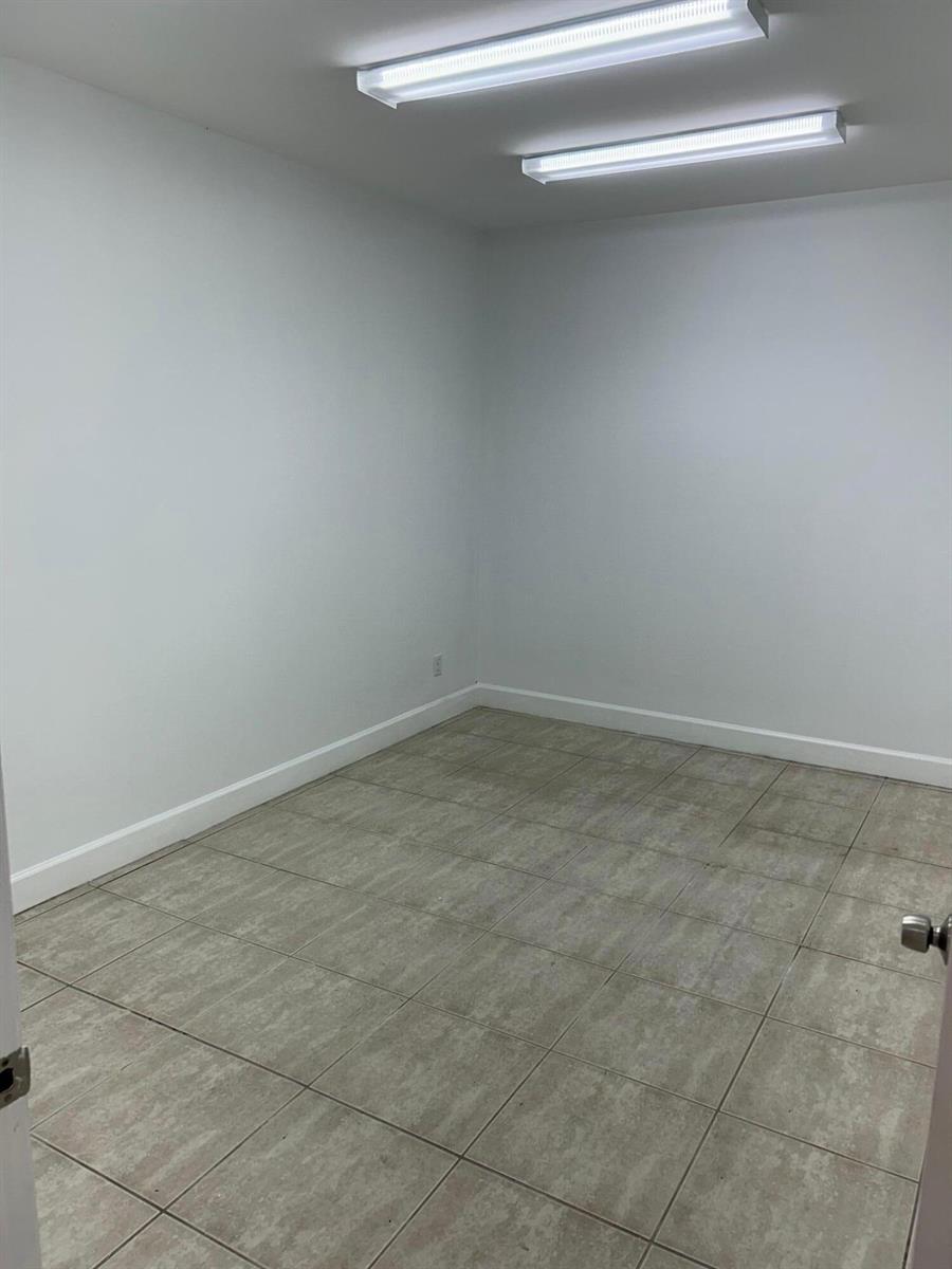 An empty room features white walls, a tiled floor, and two rectangular ceiling light fixtures — 1746 SW Biltmore Street # 1746, FL 34984, FL