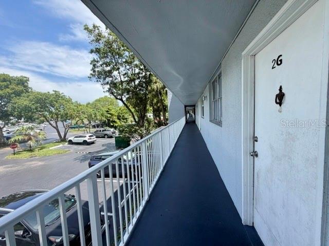 An outdoor apartment walkway overlooks a parking lot with trees under a blue sky — 107 ROYAL PARK DRIVE UNIT 2G, OAKLAND PARK, FL