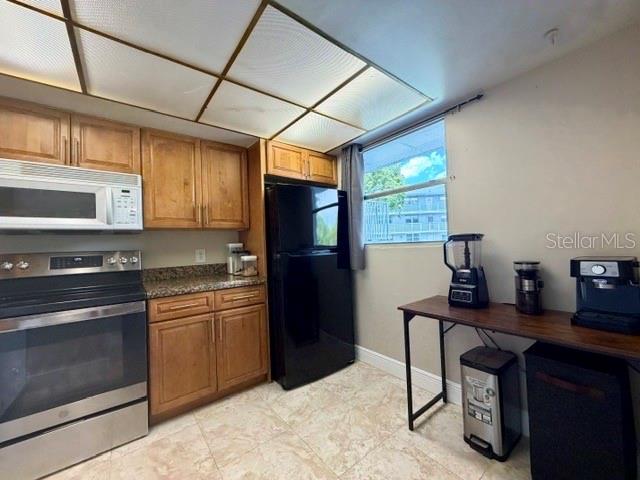 A kitchen features wood cabinets, stainless steel appliances, a black refrigerator, and tile flooring — 107 ROYAL PARK DRIVE UNIT 2G, OAKLAND PARK, FL