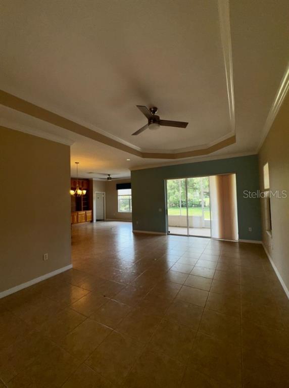 A spacious living area with tile flooring, a tray ceiling, and sliding glass patio doors — 8821 SW 82ND COURT ROAD, OCALA, FL