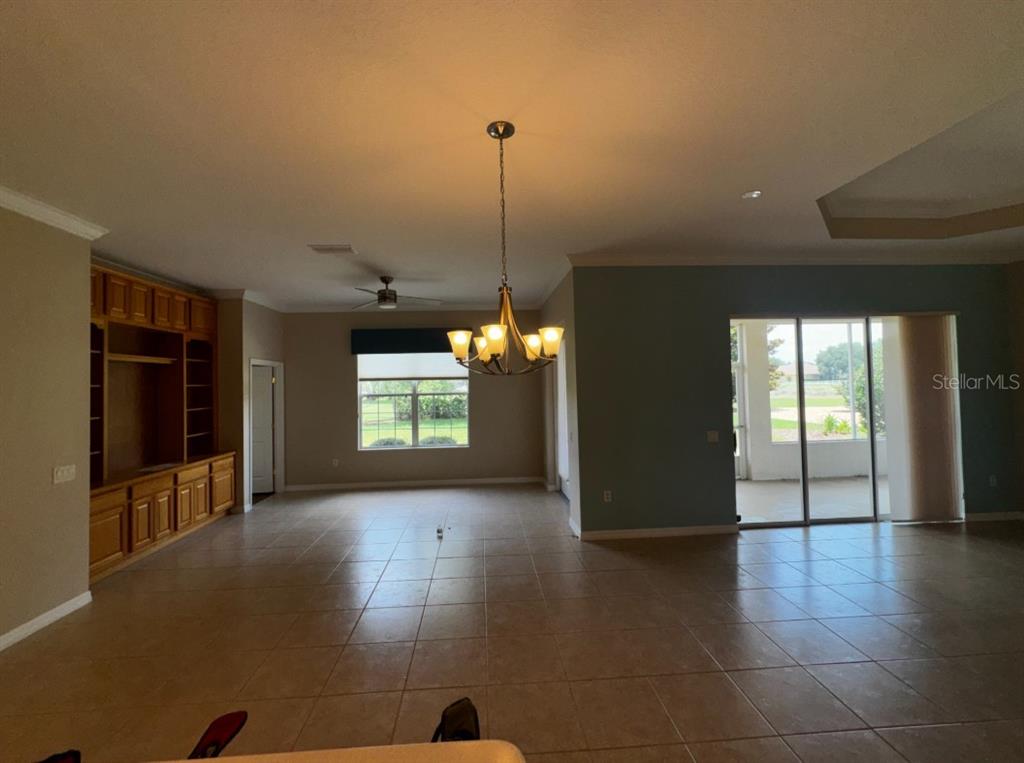 A spacious living area features tile flooring, a built-in wooden entertainment center, and sliding doors — 8821 SW 82ND COURT ROAD, OCALA, FL