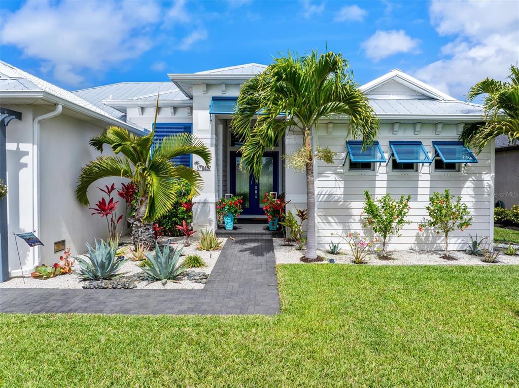 A white house with a metal roof, blue shutters, and a palm tree-lined front yard — 8407 DAFOE STREET, PORT CHARLOTTE, FL