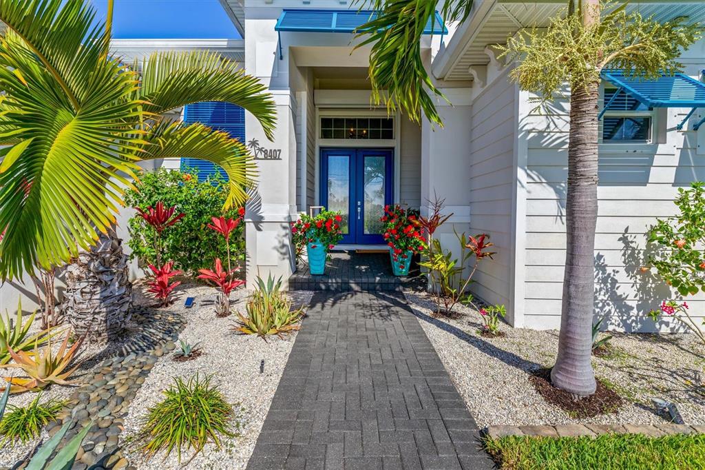 A paved walkway leads to the blue double front doors of a coastal-style home — 8407 DAFOE STREET, PORT CHARLOTTE, FL