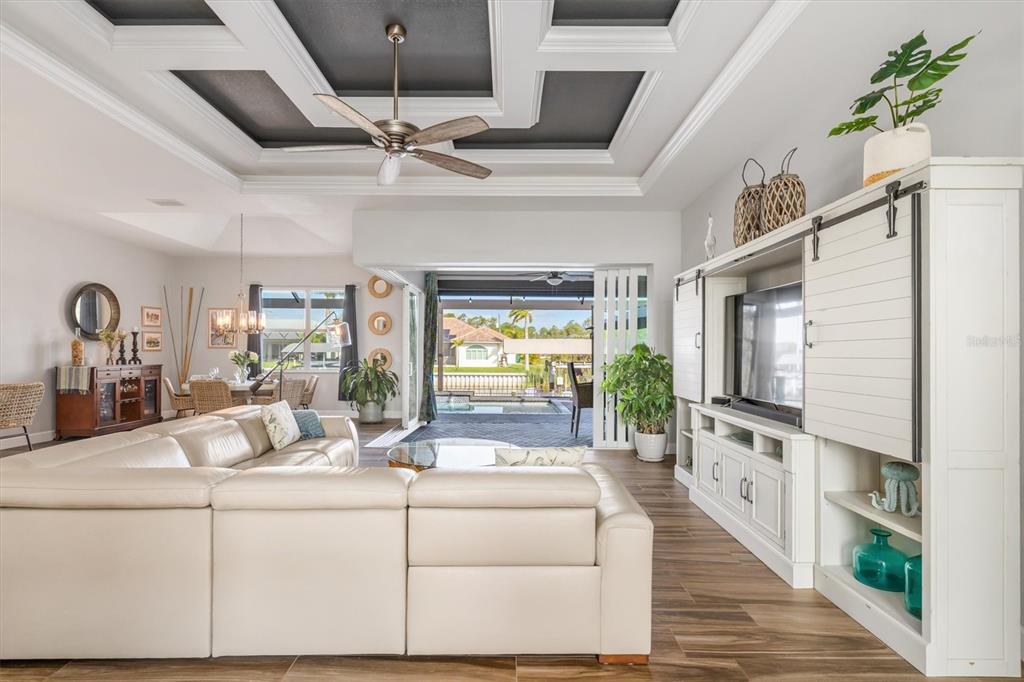 A living room with a coffered ceiling, white sectional sofa, and sliding doors to a pool — 8407 DAFOE STREET, PORT CHARLOTTE, FL